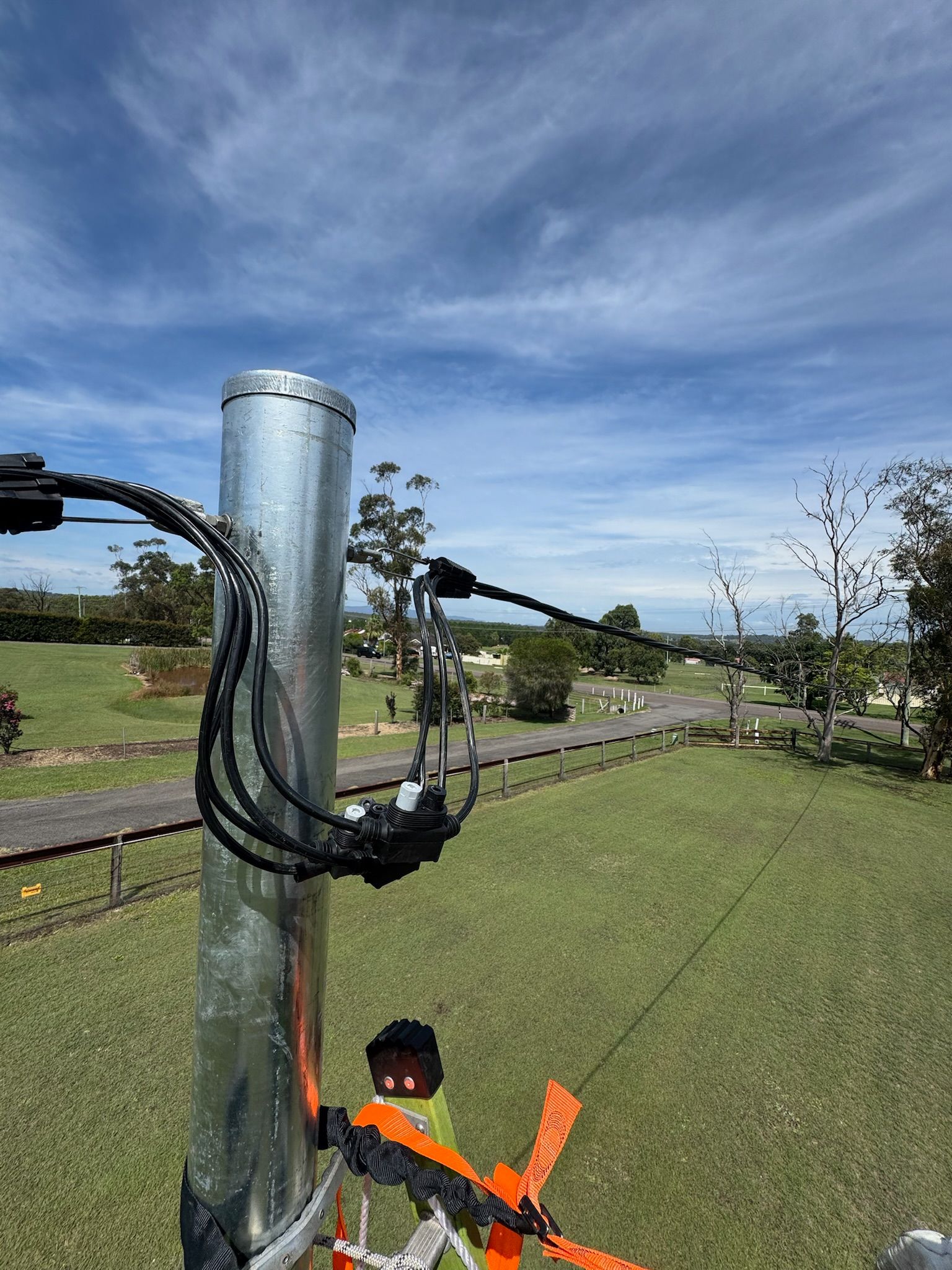 Orange windsock on a metal pole in a grassy field under a blue sky — DMP Electrical Contractors In Kurri Kurri, NSW
