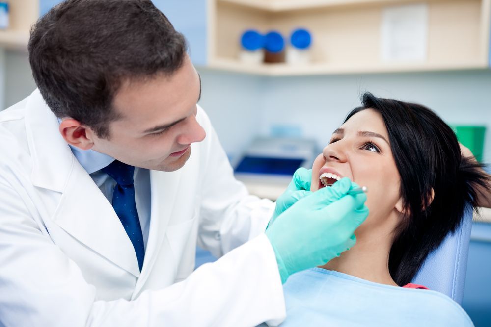 A Dentist is Examining a Woman's Teeth in a Dental Office — Parap Family Dental in Parap, NT