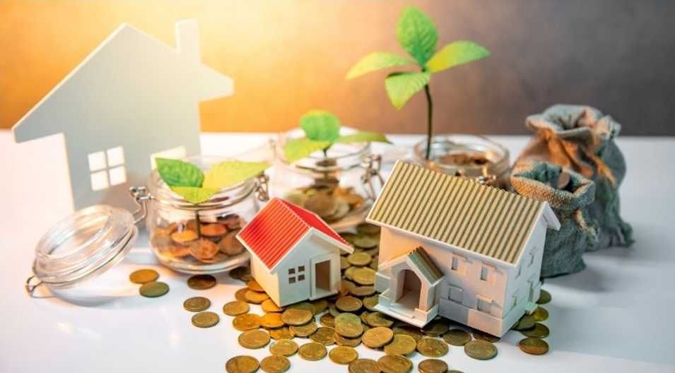 Miniature houses, coins, and sprouting plants symbolize home investment and growth.
