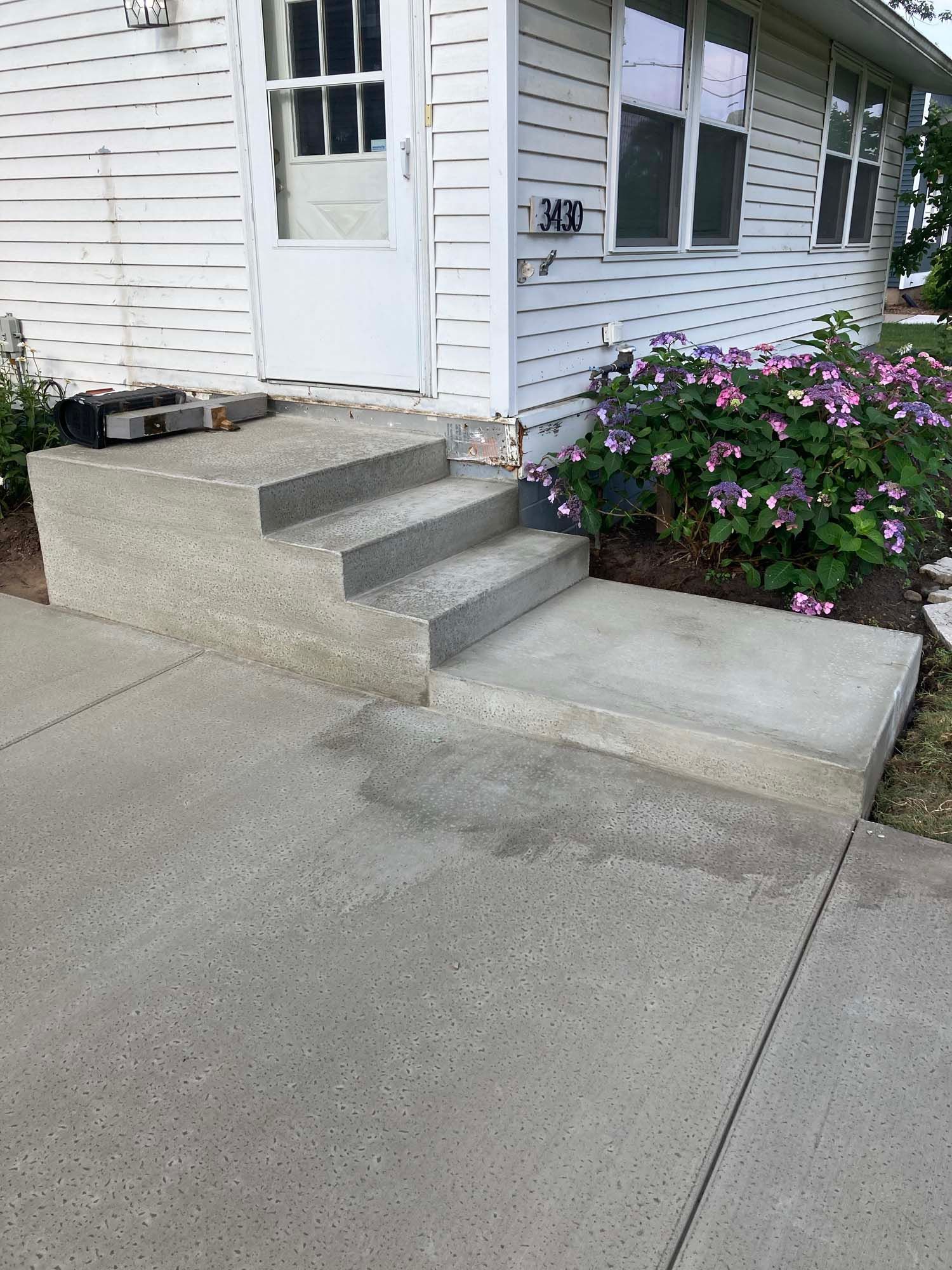 A concrete driveway with a wooden fence in the background.
