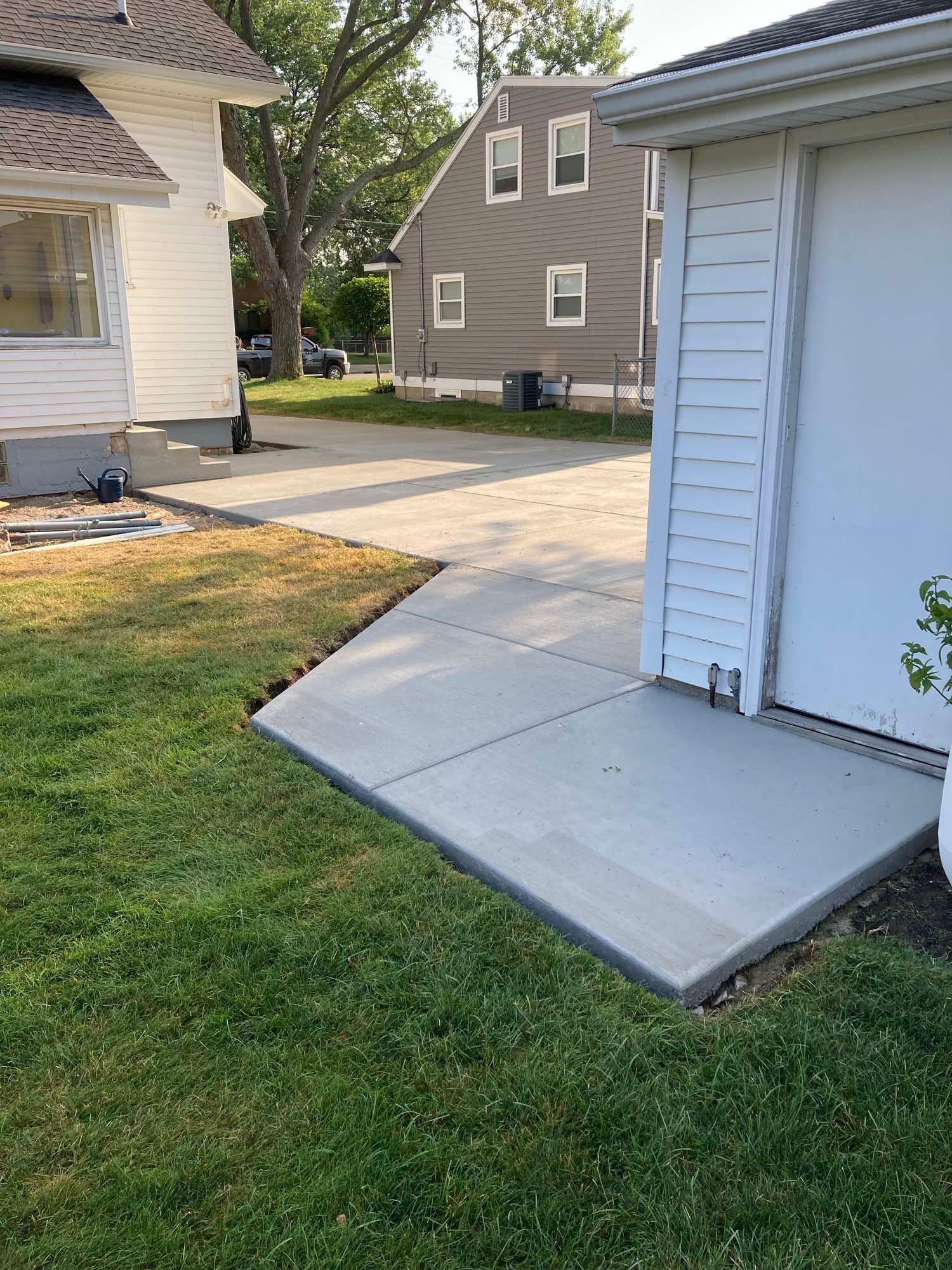 A concrete driveway with a wooden fence in the background.