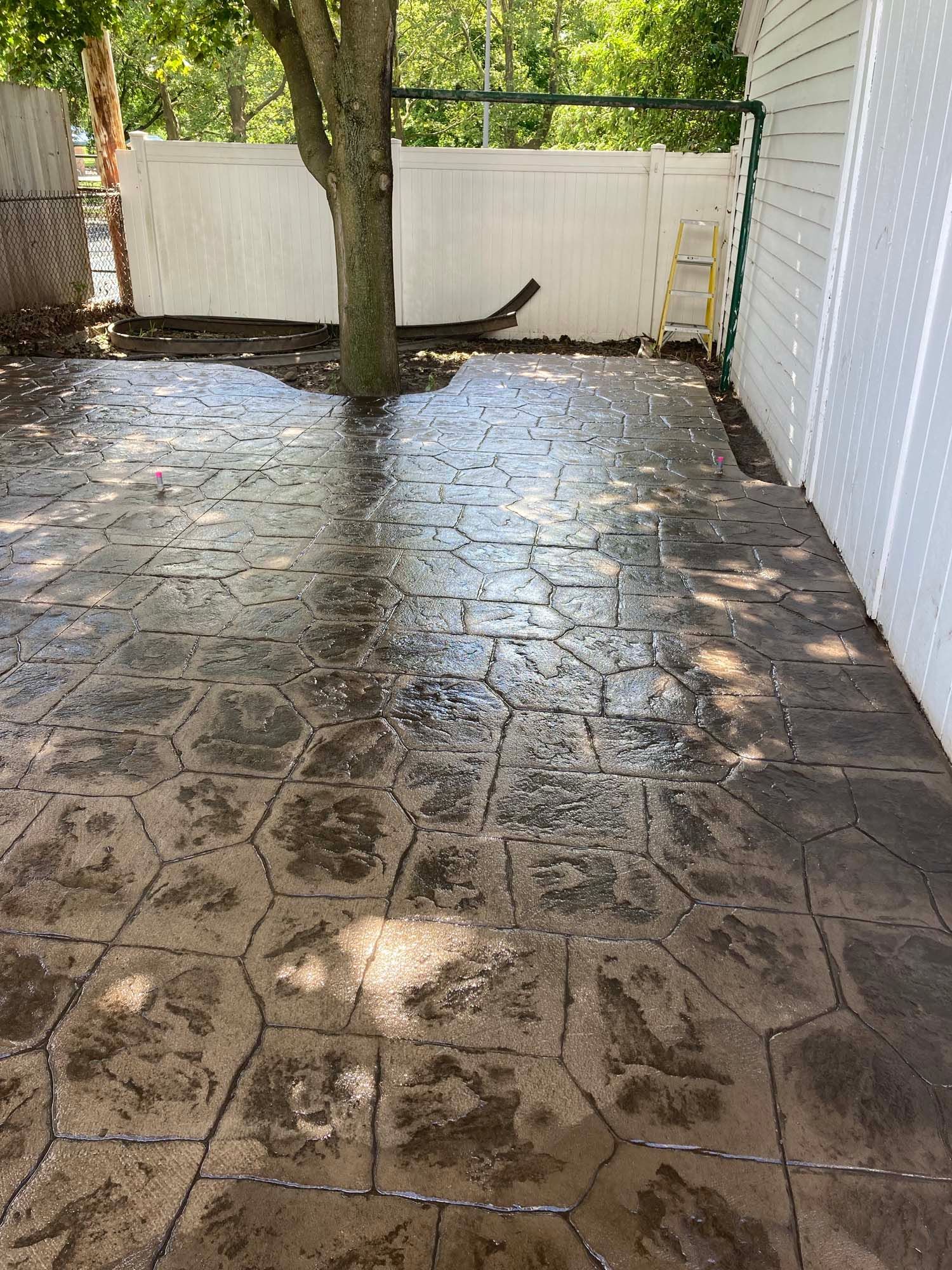 A concrete driveway with a wooden fence in the background.