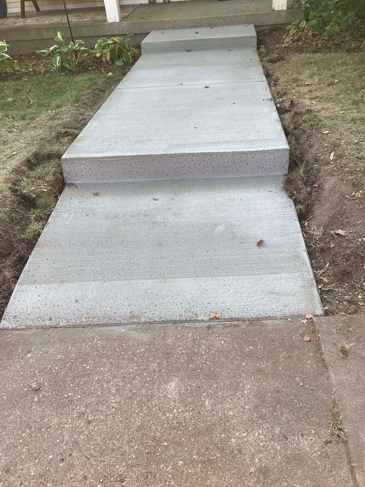 A concrete driveway with a wooden fence in the background.