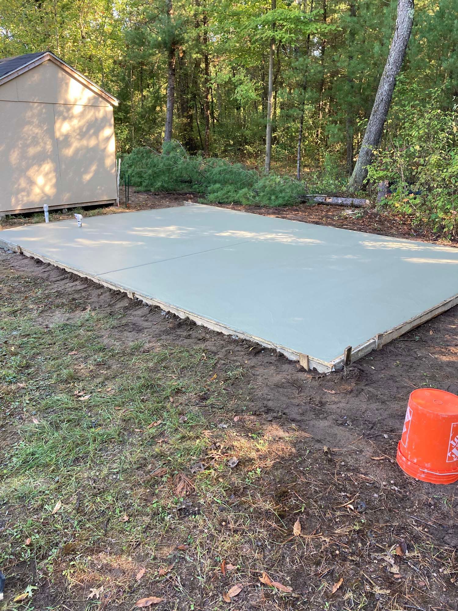 A concrete driveway with a wooden fence in the background.