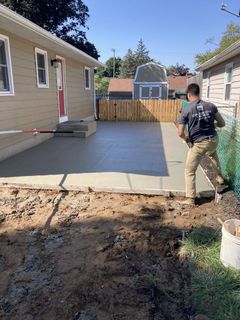 A man is working on a concrete driveway in front of a house.