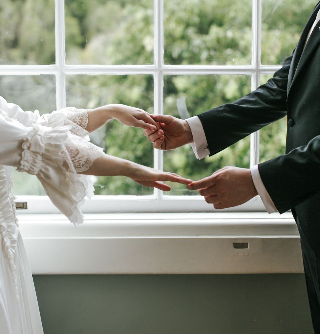 Bride and groom hands in hands close to a window of a palace in Sintra, Portugal
