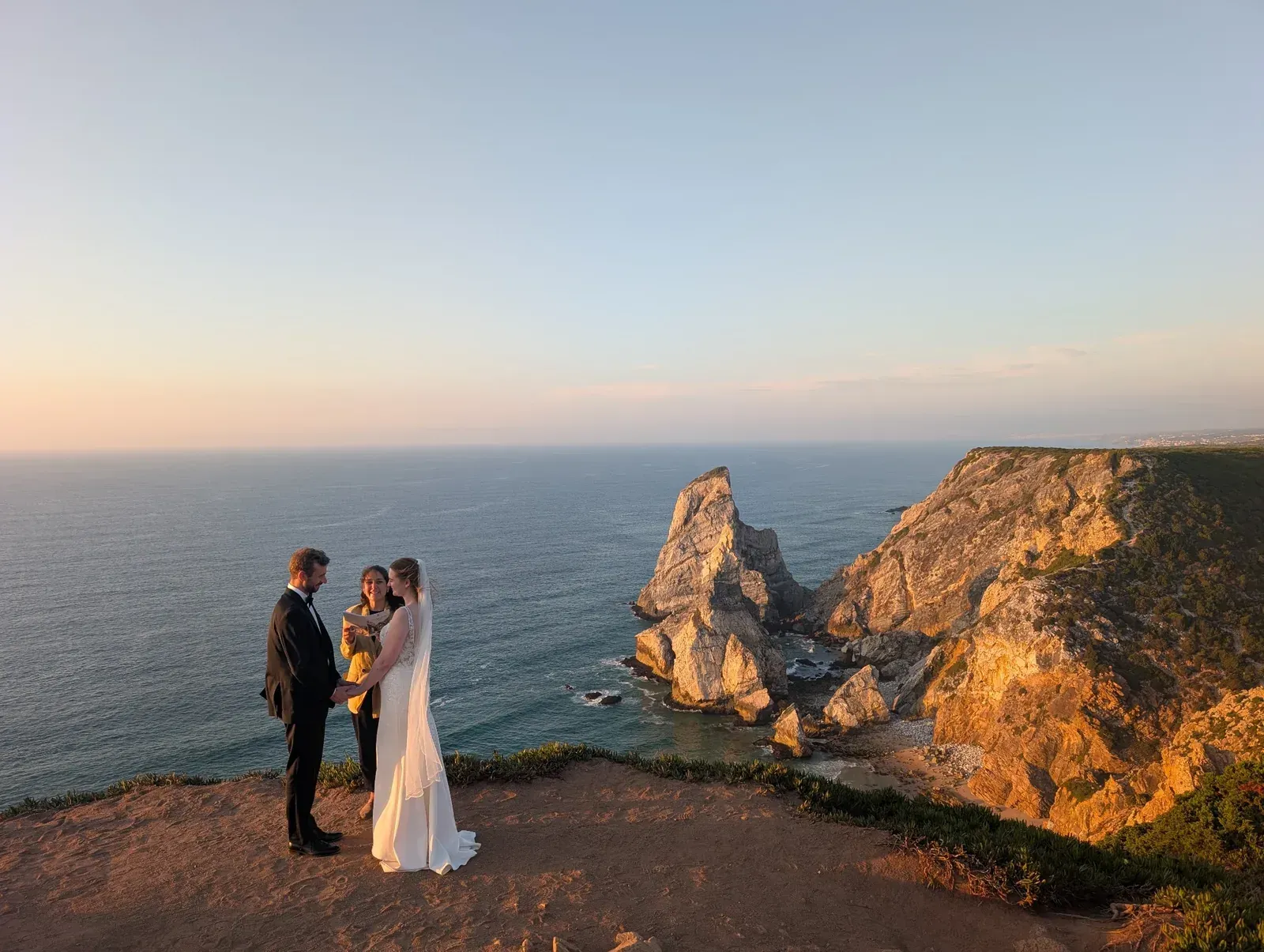Couple exchanging vows with their celebrant overlooking Praia da Ursa, Sintra, Portugal.