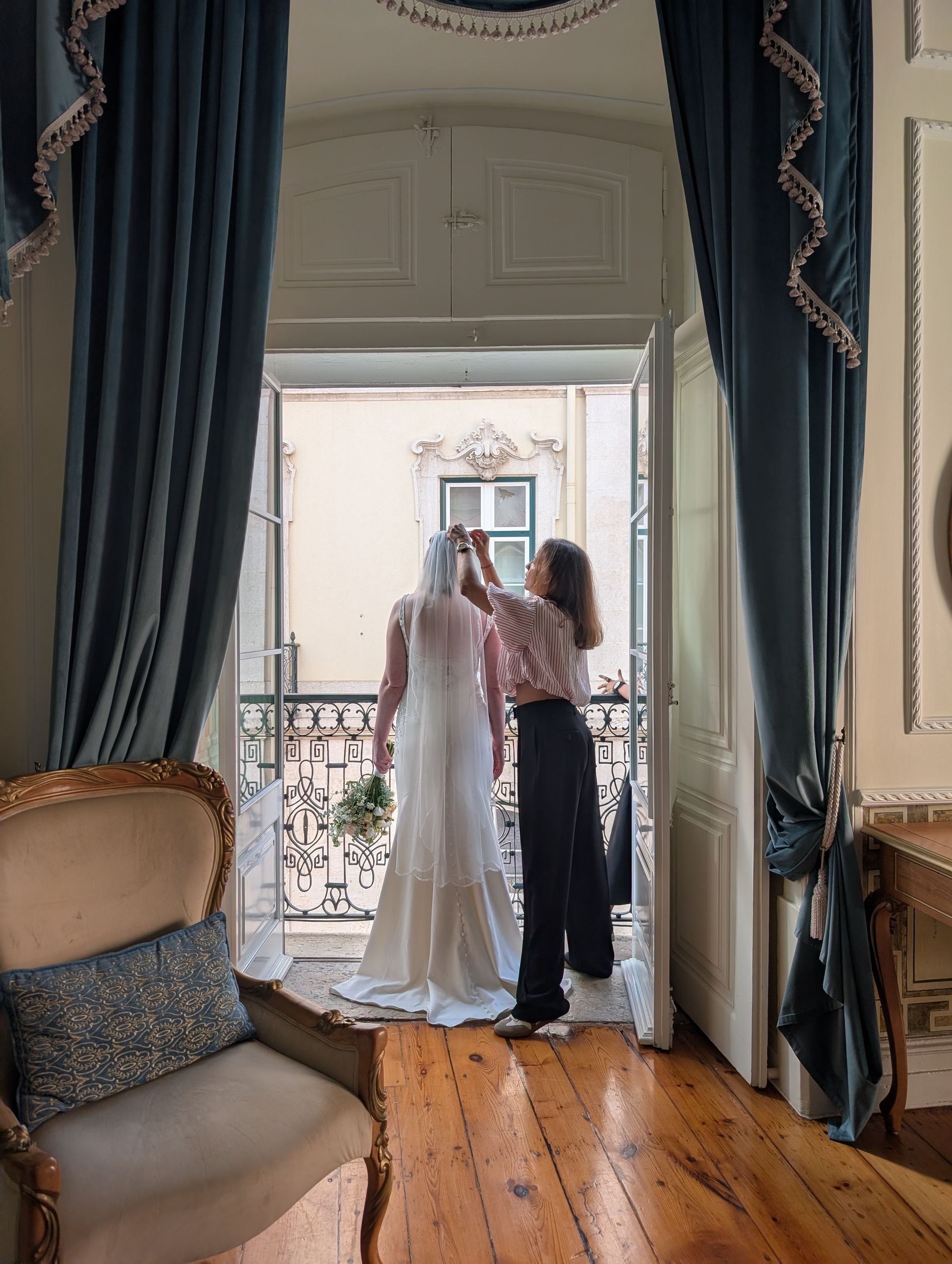 Uma maquilhadora coloca o véu na cabeça da noiva. Estão numa varanda do Hotel Palácio das Especiarias, em Lisboa.