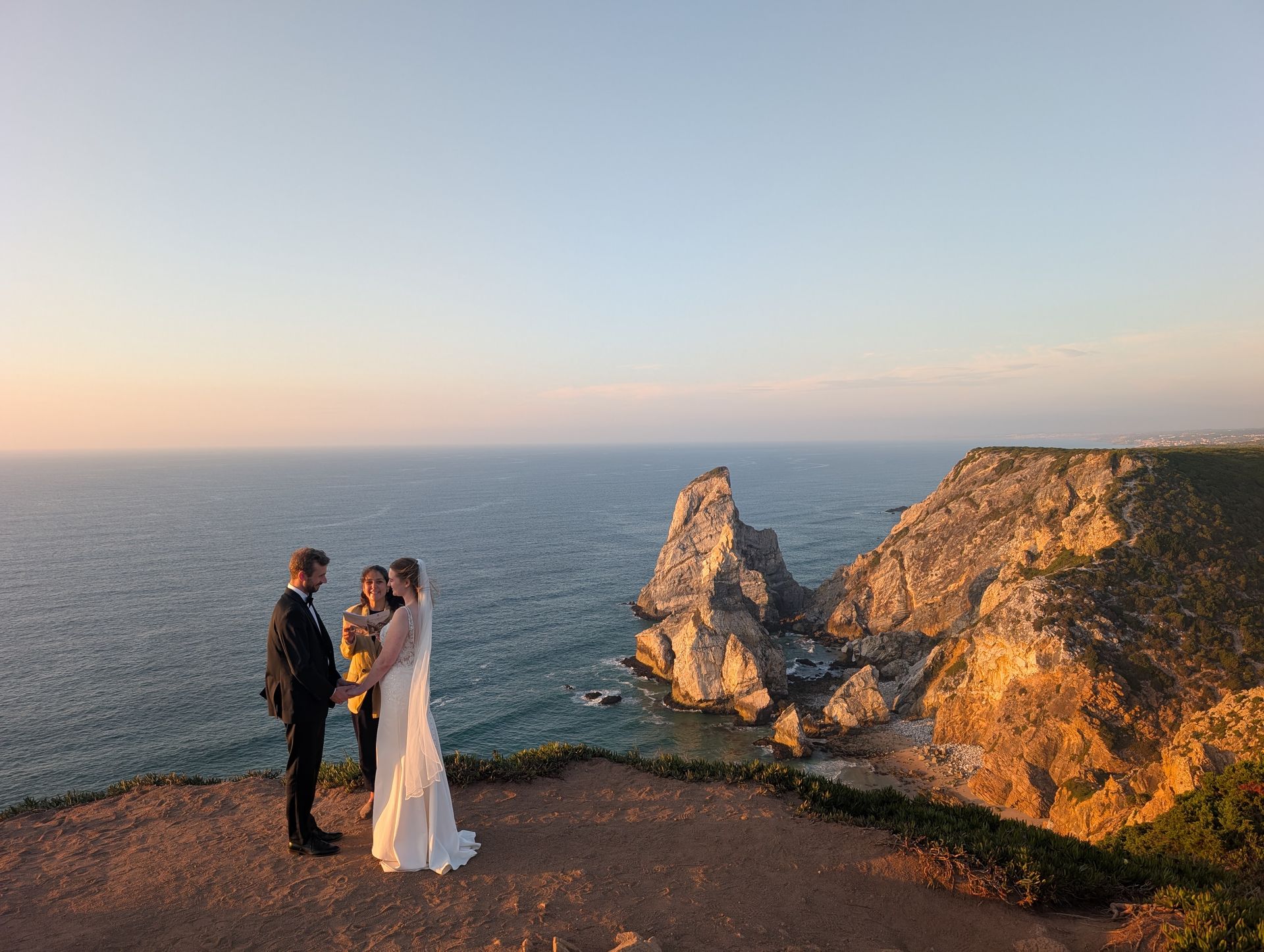 Couple exchanging vows with their celebrant overlooking Praia da Ursa, Sintra, Portugal.