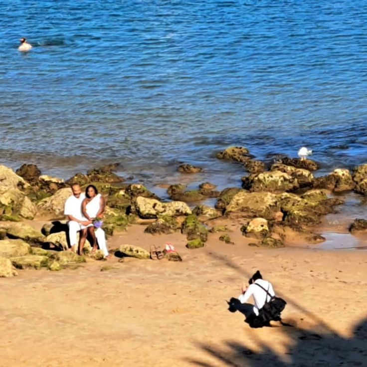 Couple seating on the rocks of Cascais beach, Portugal during a photo session.