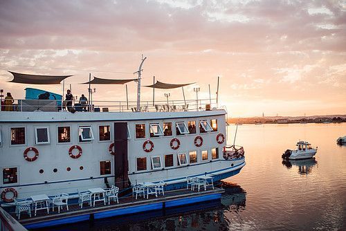 A charming riverboat with a sunset in the background, set up for a wedding celebration.