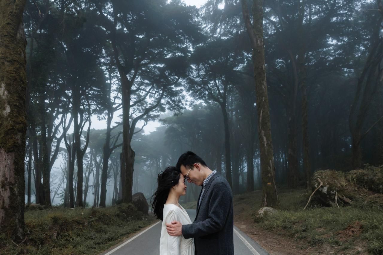 Couple embracing on a misty forest road surrounded by trees in Sintra, Portugal.