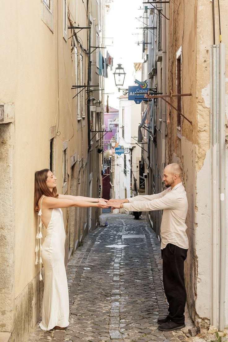 Bride and groom holding hands and walking towards each other down a narrow colourful alley in Lisbon.