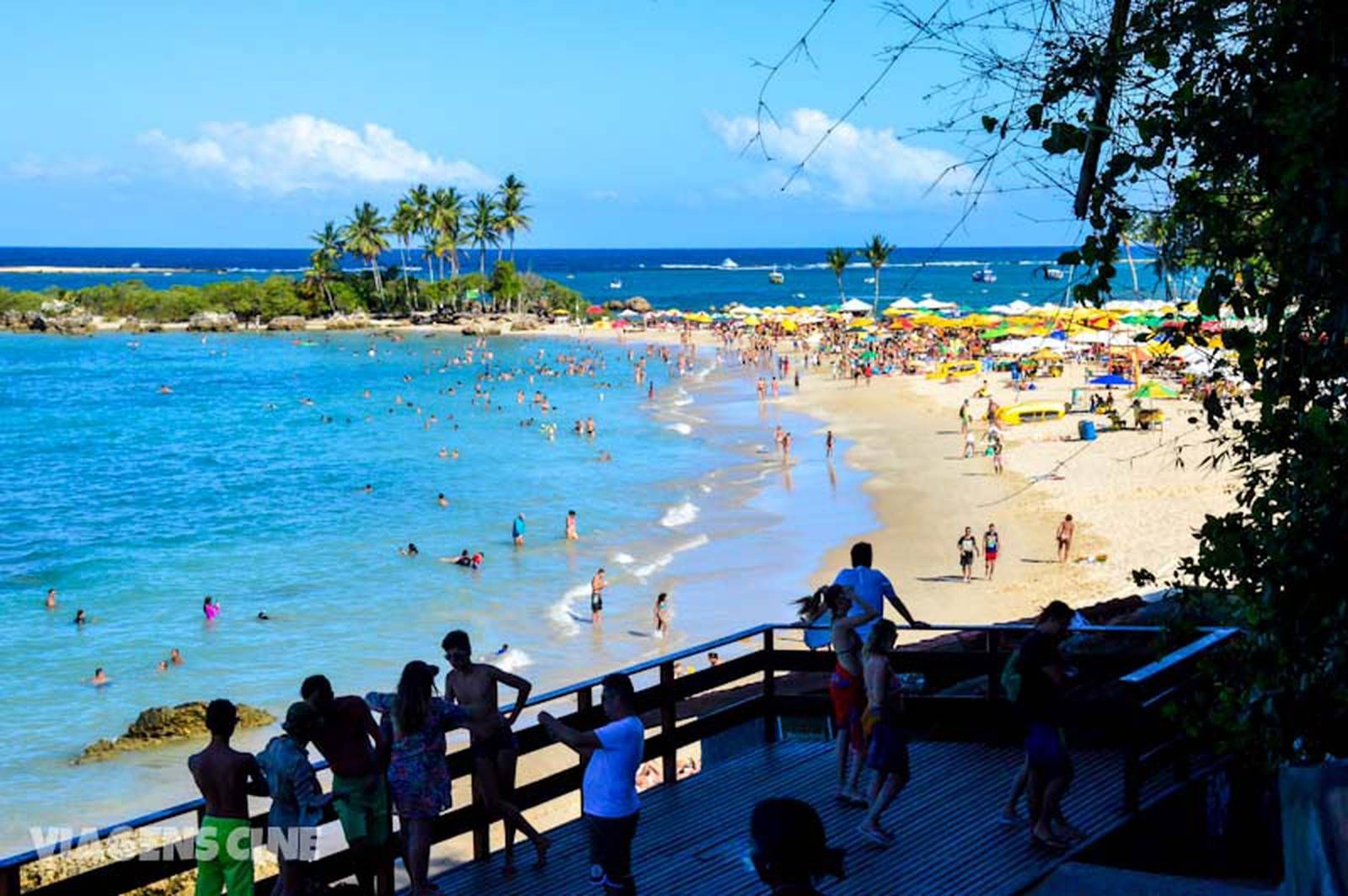 Um grupo de pessoas em pé em um calçadão com vista para uma praia