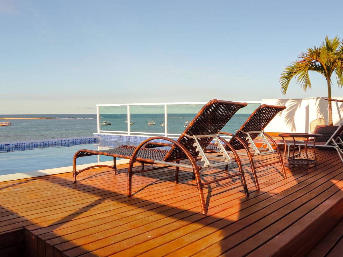 Um deck com cadeiras e uma piscina com vista para o oceano