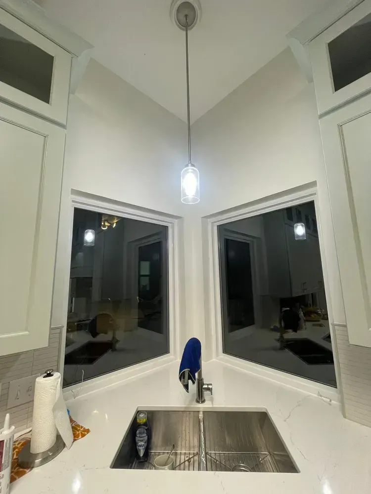 A kitchen with a sink , faucet , and two windows.