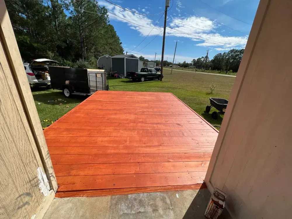A wooden deck with a trailer parked in the background.
