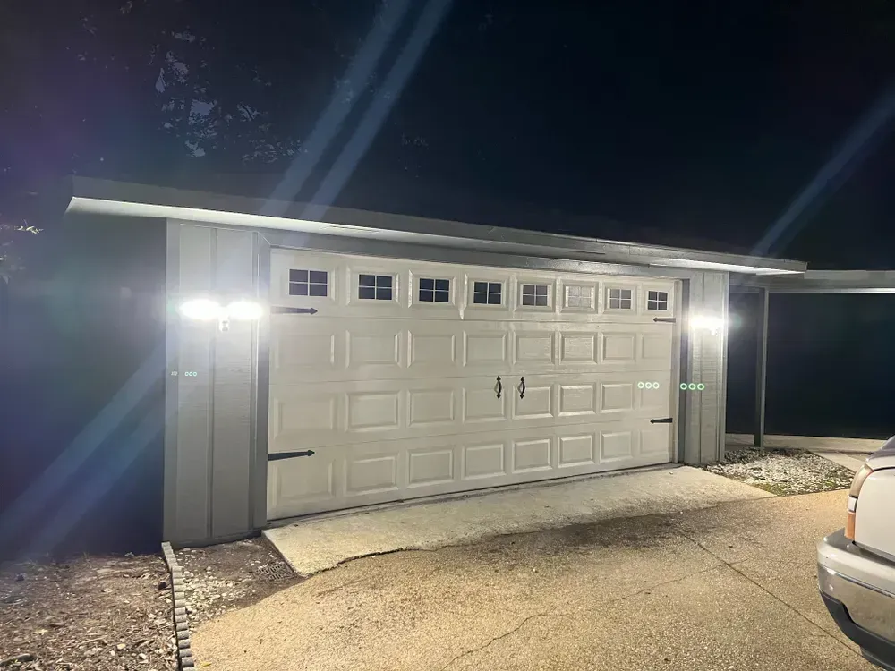 A car is parked in front of a garage door at night.