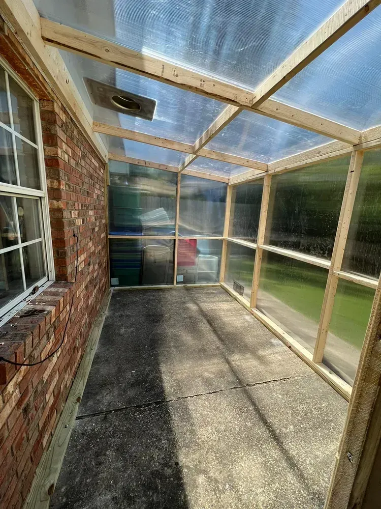 A brick house with a screened in porch with a clear plastic roof.