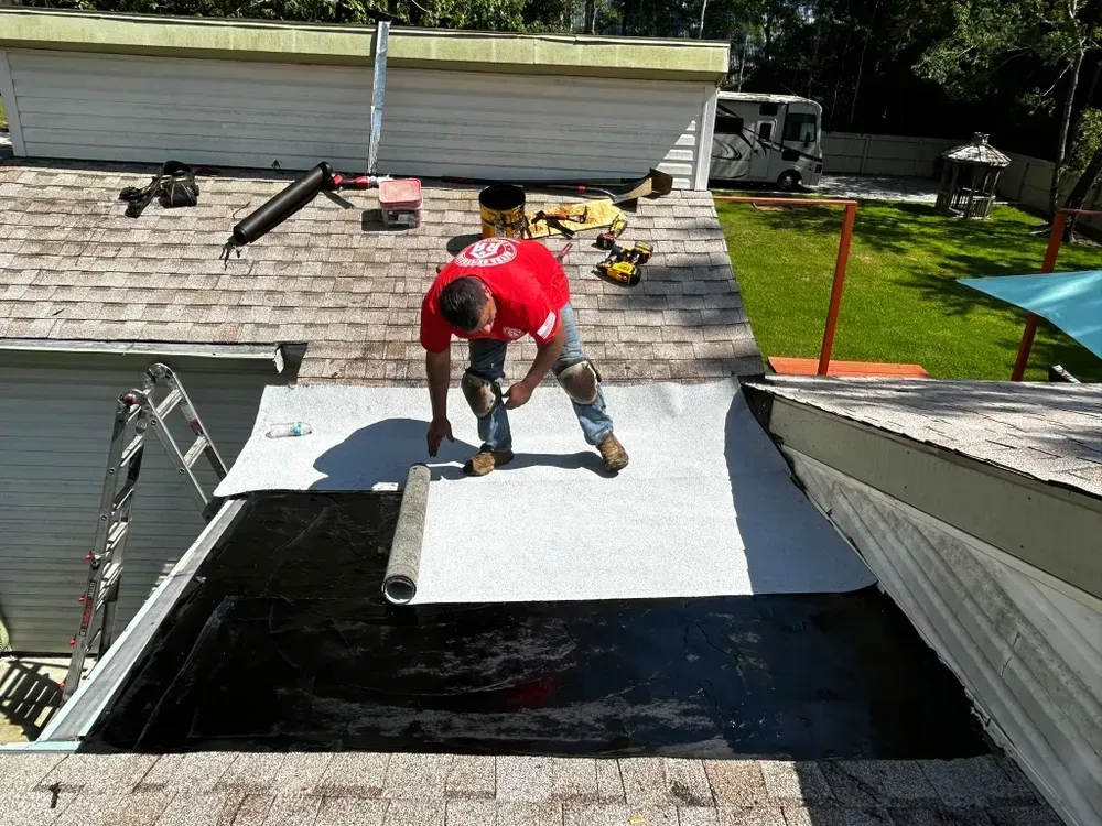 A man in a red shirt is working on a roof.