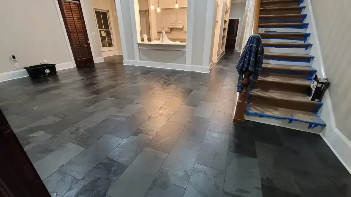 A living room with a black tile floor and stairs.