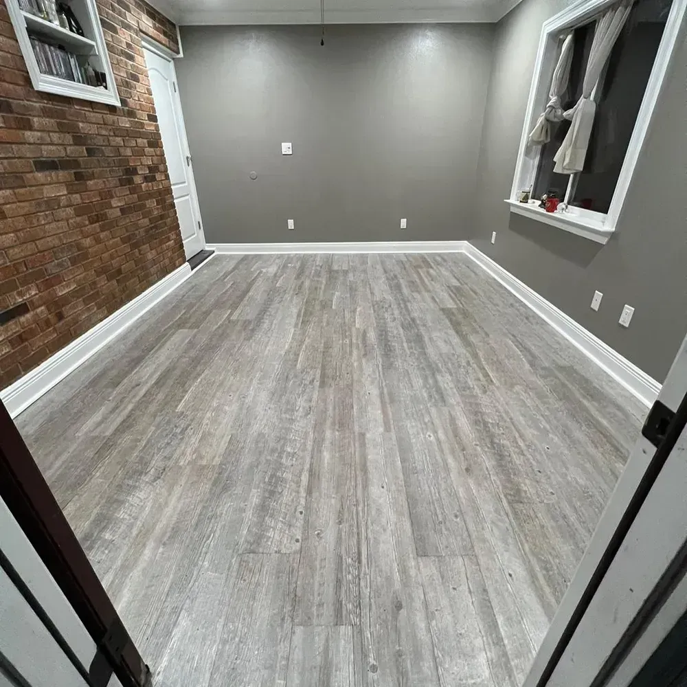 A room with hardwood floors and a brick wall.