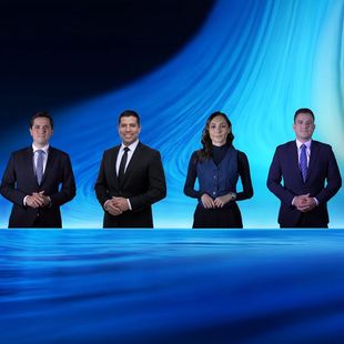 A group of people are posing for a picture in a news studio.