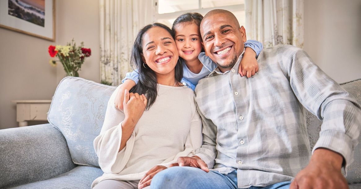 Smiling family sitting together on a couch in a bright living room
