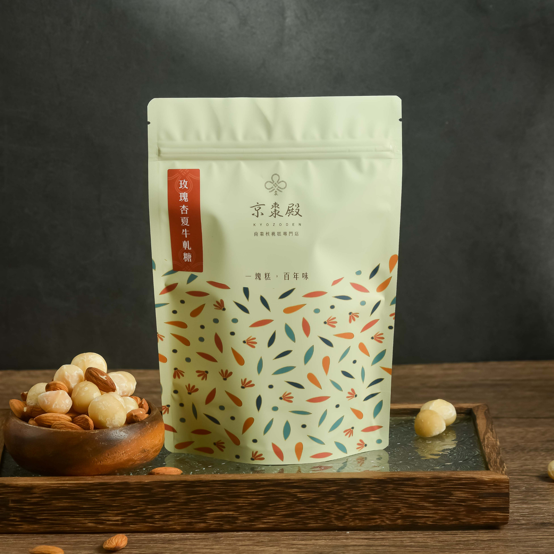 奶油色的零食袋放在木托盤上，旁邊放著一小碗堅果，托盤上有彩色葉子圖案。
