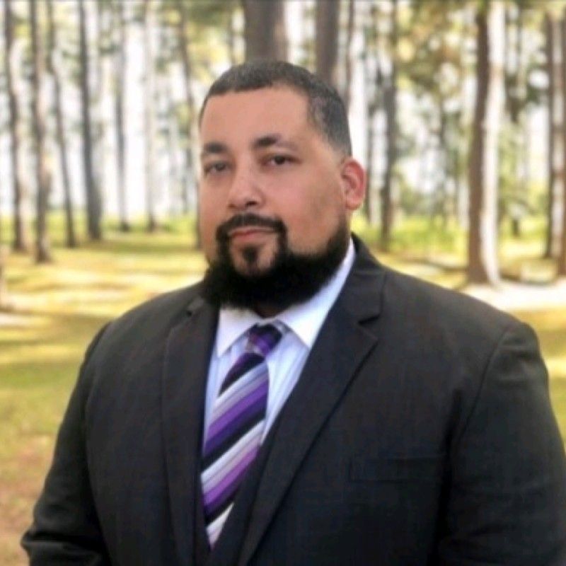A picture of Commissioner Emmitt Eldridge who has a beard and is wearing a suit and tie.