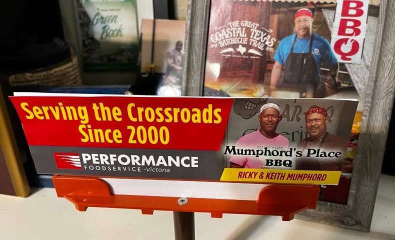 Red barbecue trailer sign with “Serving the Crossroads Since 2000” and Mumphord’s Place BBQ branding