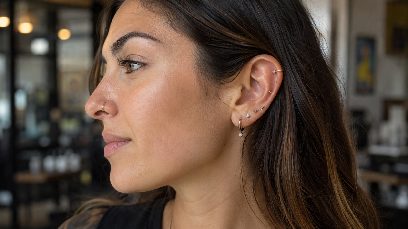 Curated ear piercings with healed studs and hoops shown on an adult client in a professional piercing studio.