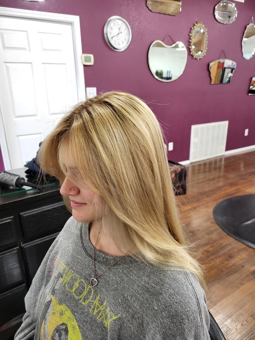 A woman with blonde hair is sitting in a chair in a salon.