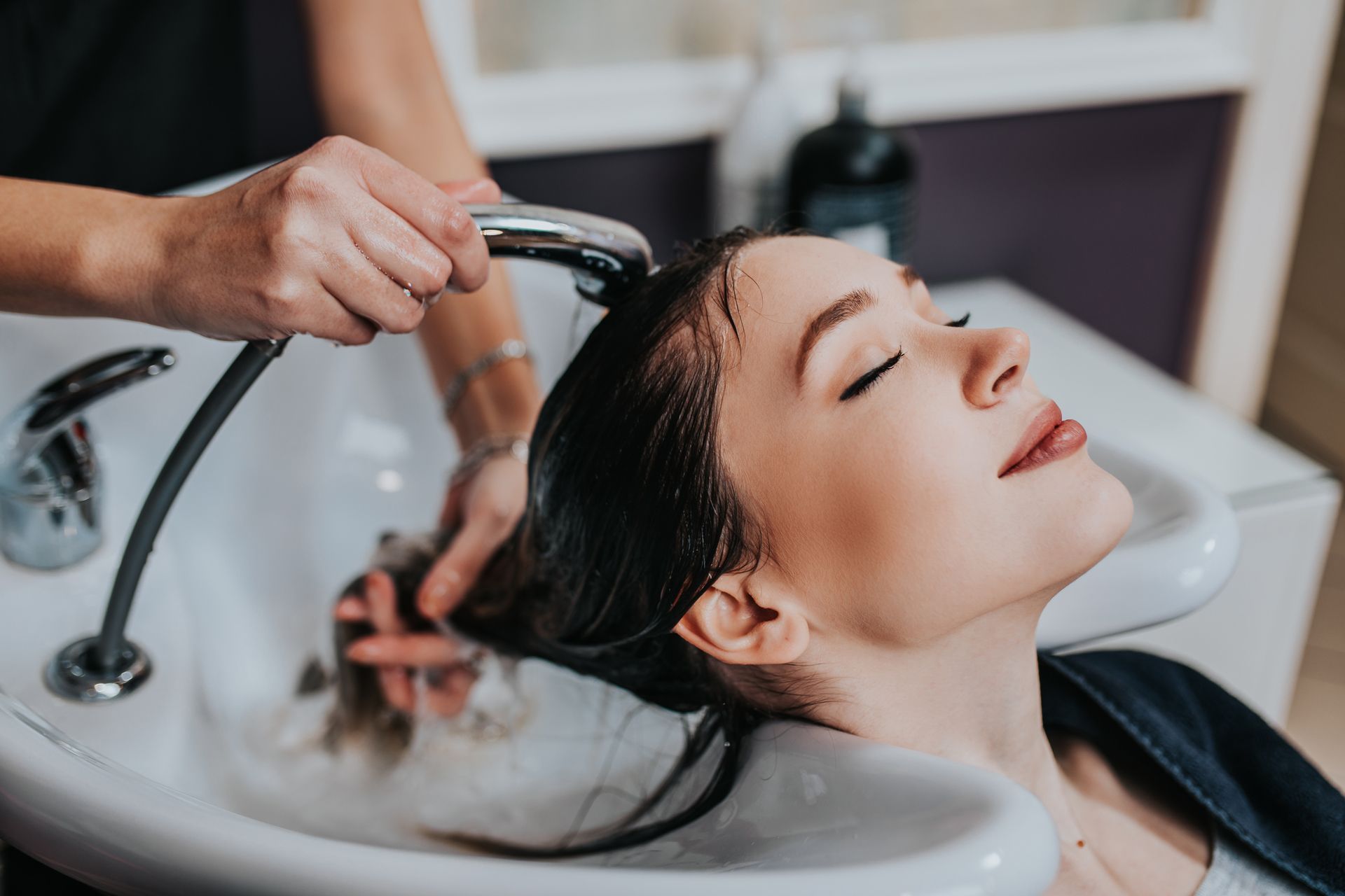 A Woman is Getting Her Hair Washed at a Hair Salon