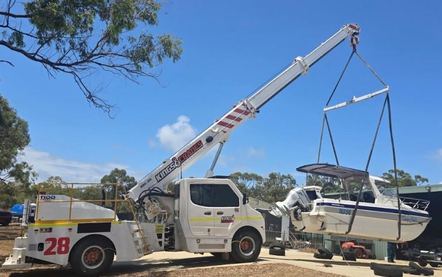 Tow Truck Lifting a White Sailboat on a Trailer in a Sunny Outdoor Lot — Kings Cranes in Bowen, QLD