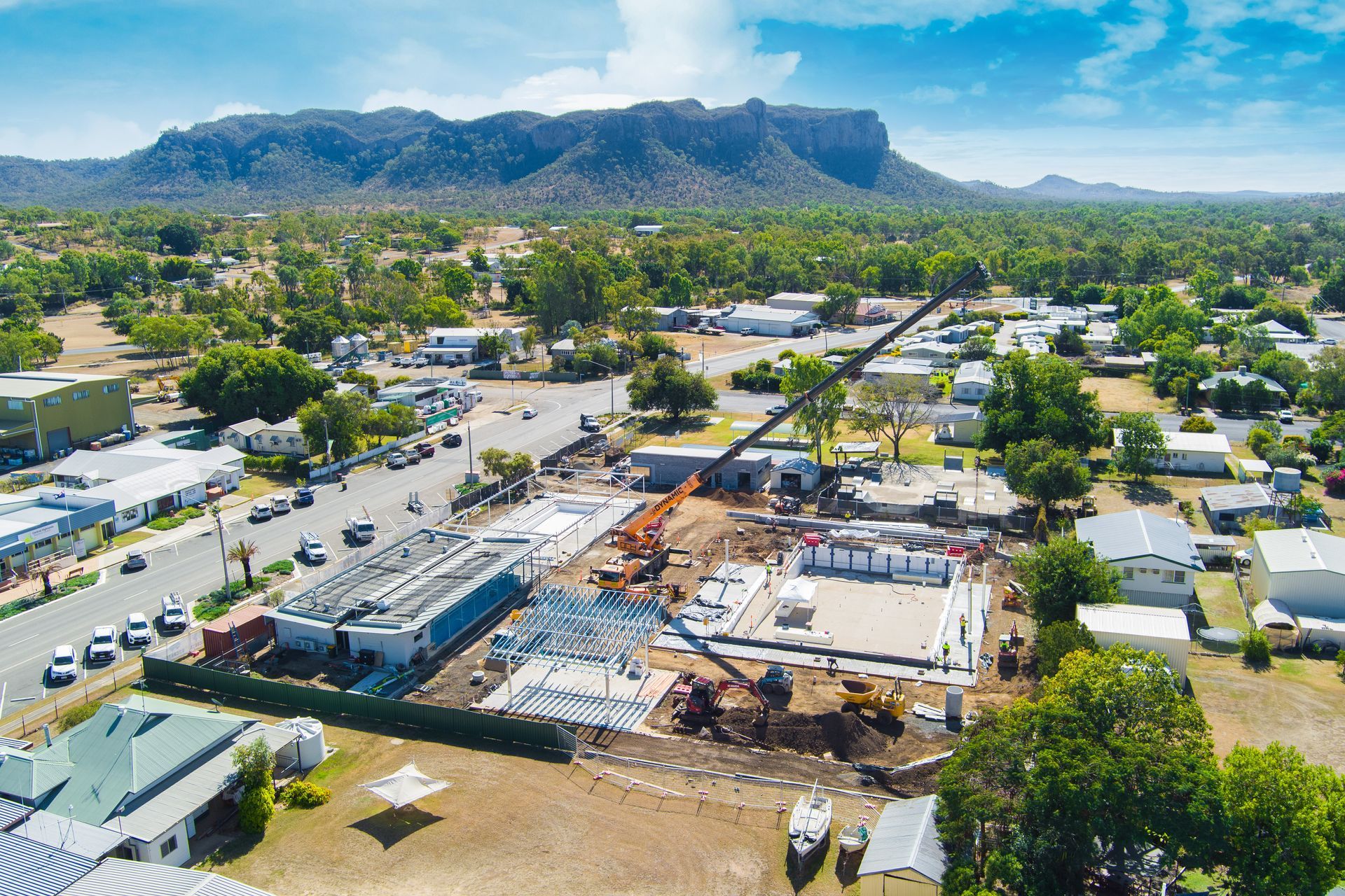 Aerial view of a town under construction, with a mountain backdrop. A crane is in use — Dynamic Crane Hire In Emerald, QLD