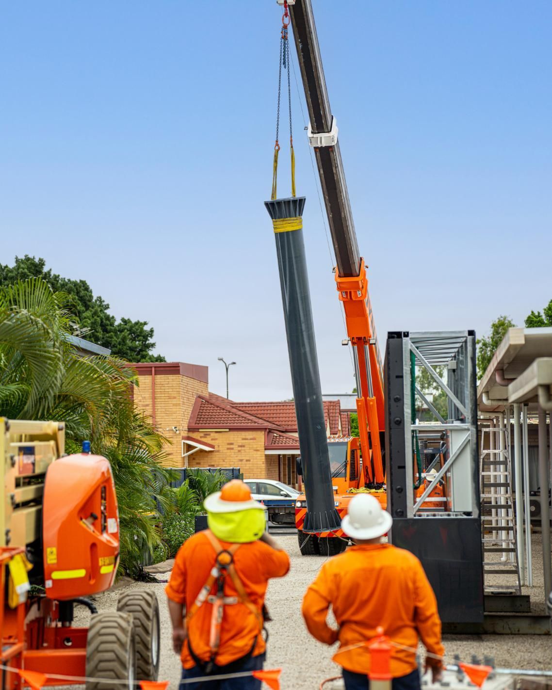 A Group Of Construction Workers Are Standing In Front Of A Crane — Dynamic Crane Hire In Emerald, QLD