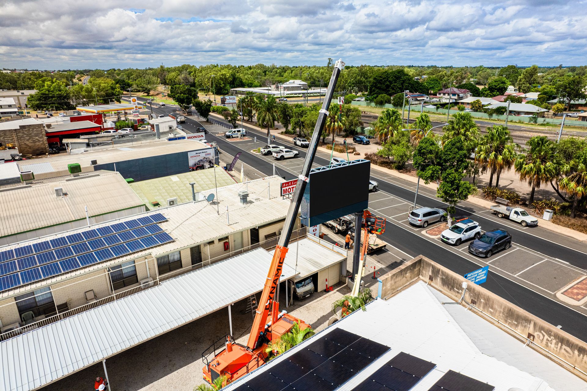 An Aerial View Of A City With A Crane Lifting A Sign On Top Of A Building — Dynamic Crane Hire In Emerald, QLD