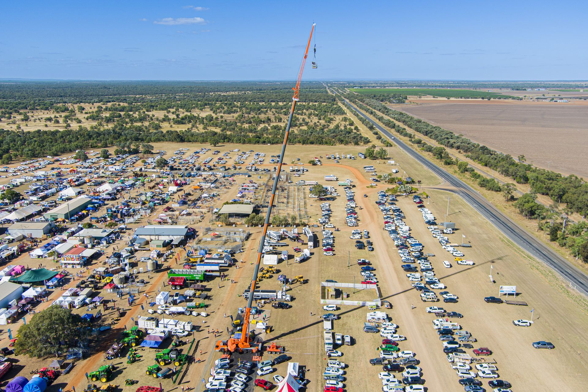 Aerial view of an outdoor event with crowds, vehicles, and a tall crane on a sunny day — Dynamic Crane Hire In Emerald, QLD