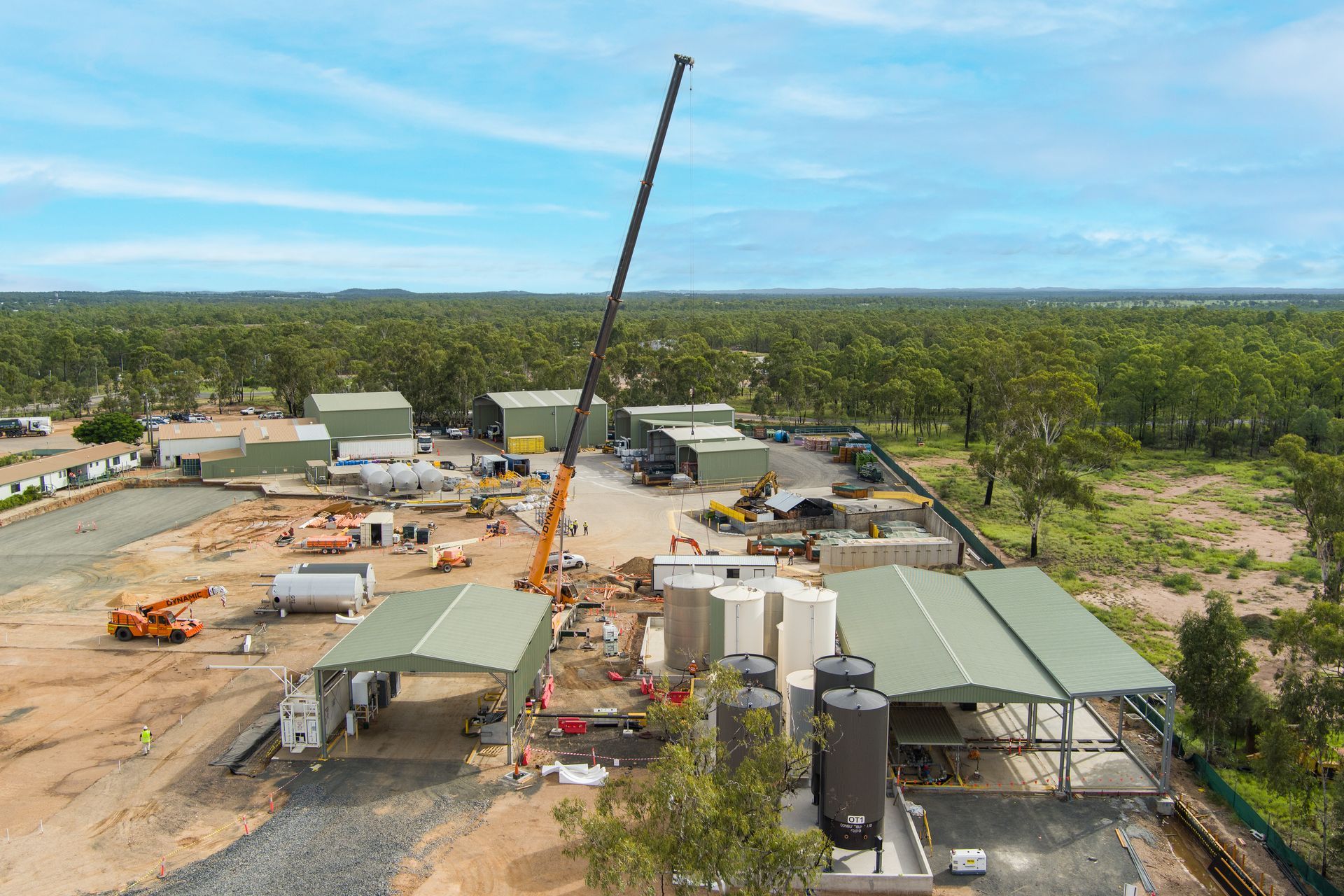 Aerial view of construction site with crane and several buildings on a gravel lot, surrounded by trees — Dynamic Crane Hire In Emerald, QLD