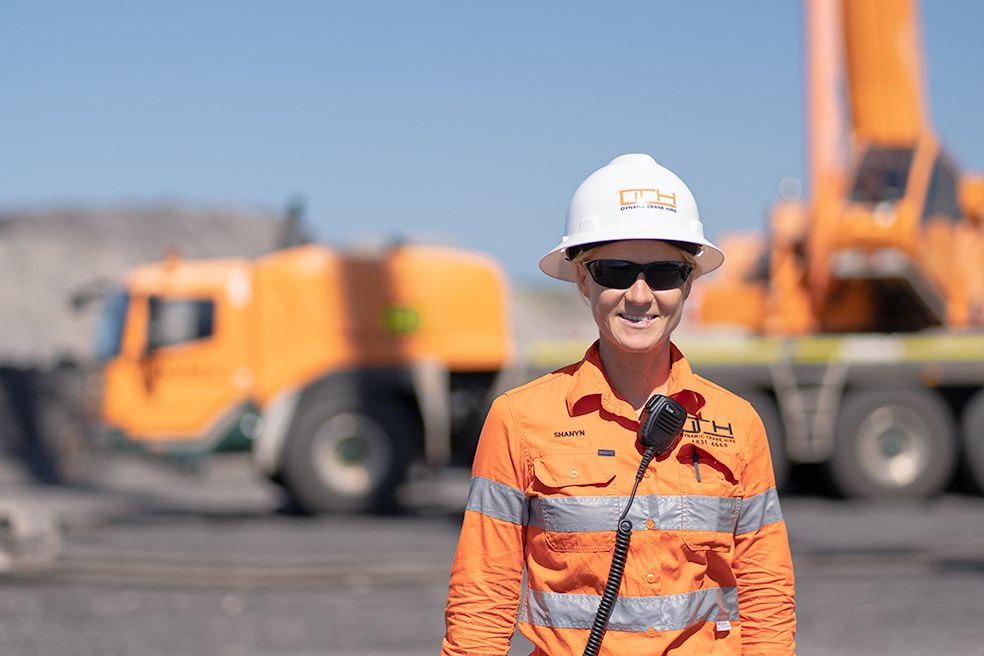 A Person Wearing A Hard Hat And Sunglasses Is Standing In Front Of A Truck — Dynamic Crane Hire In Emerald, QLD