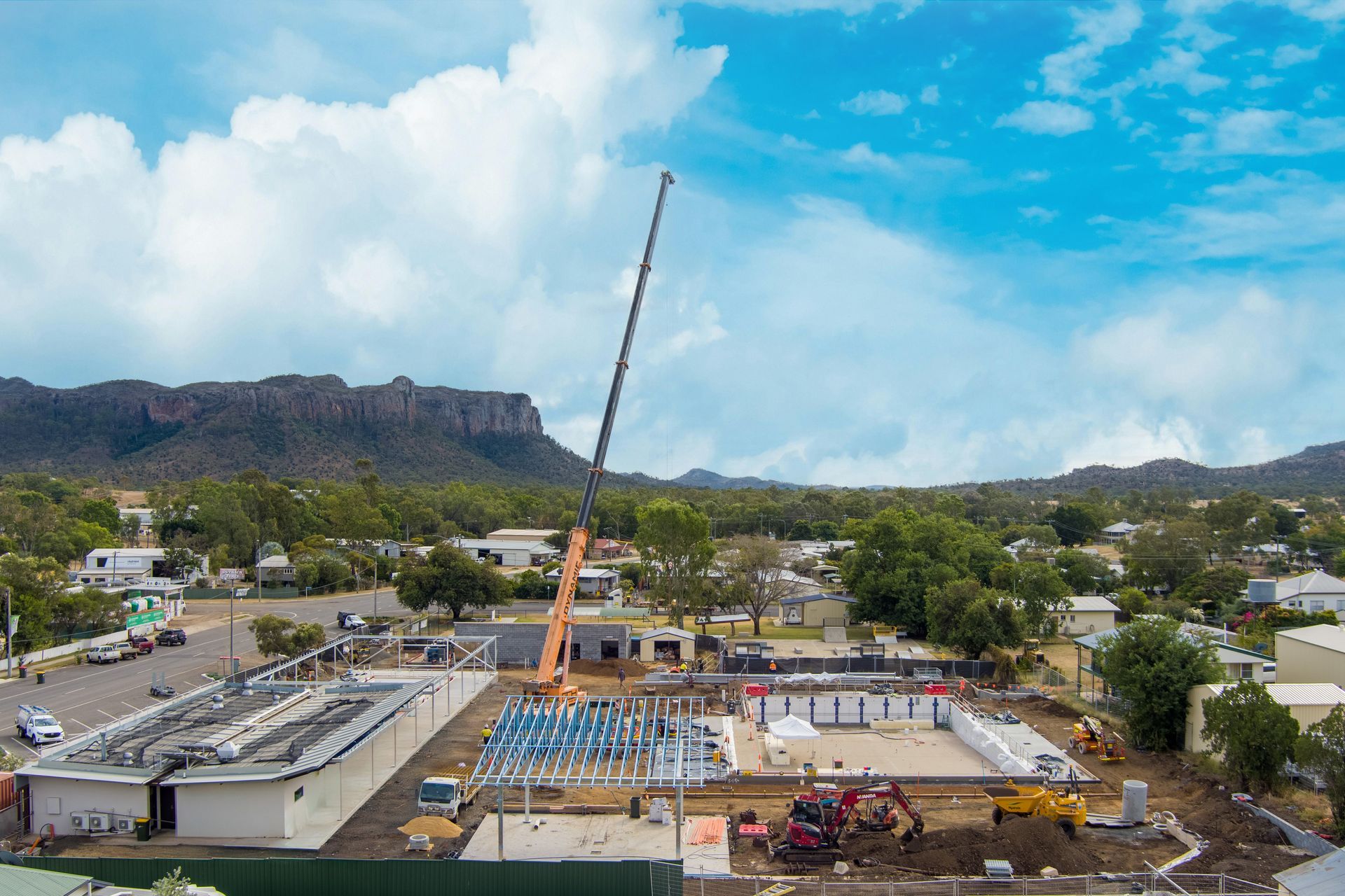 Construction site with crane, buildings, and mountains under a blue sky — Dynamic Crane Hire In Emerald, QLD