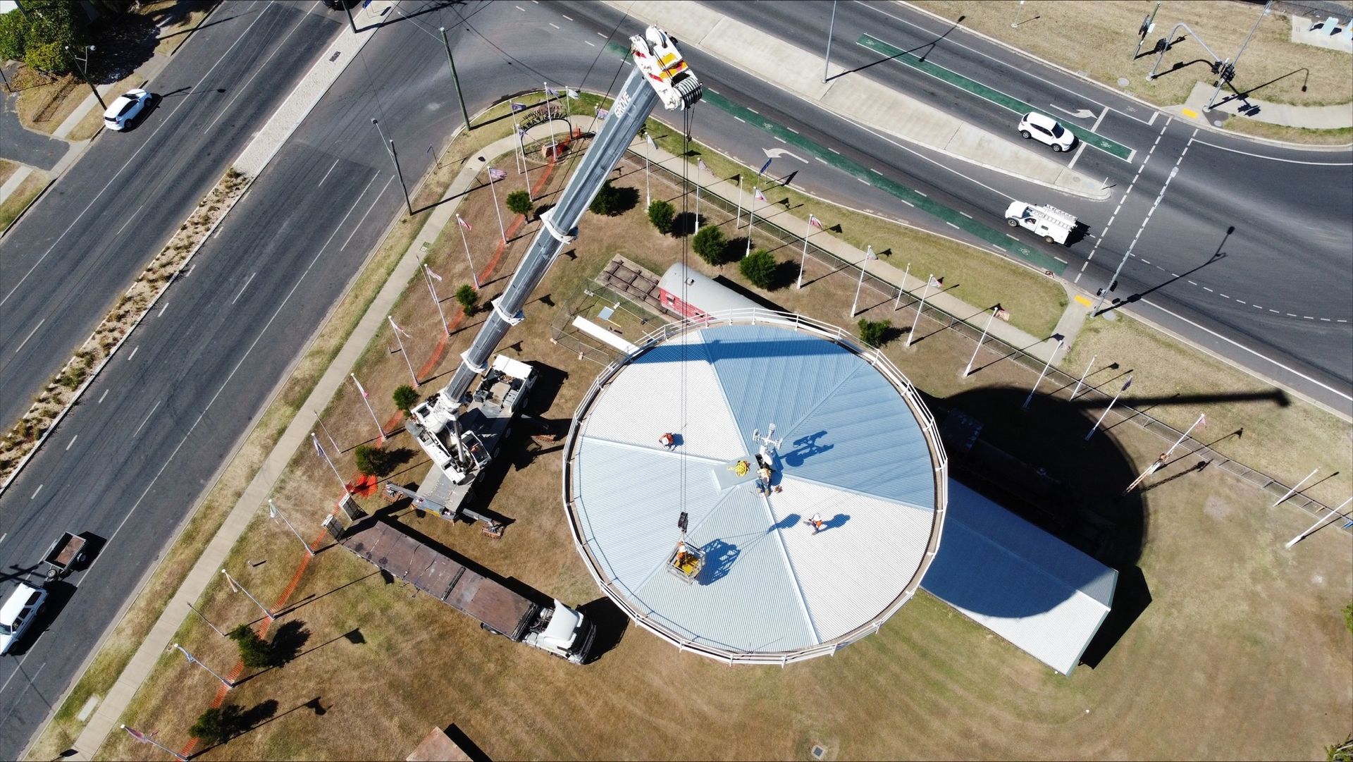 Overhead view of a crane working on a round building with a segmented roof near a road  — Dynamic Crane Hire In Emerald, QLD
