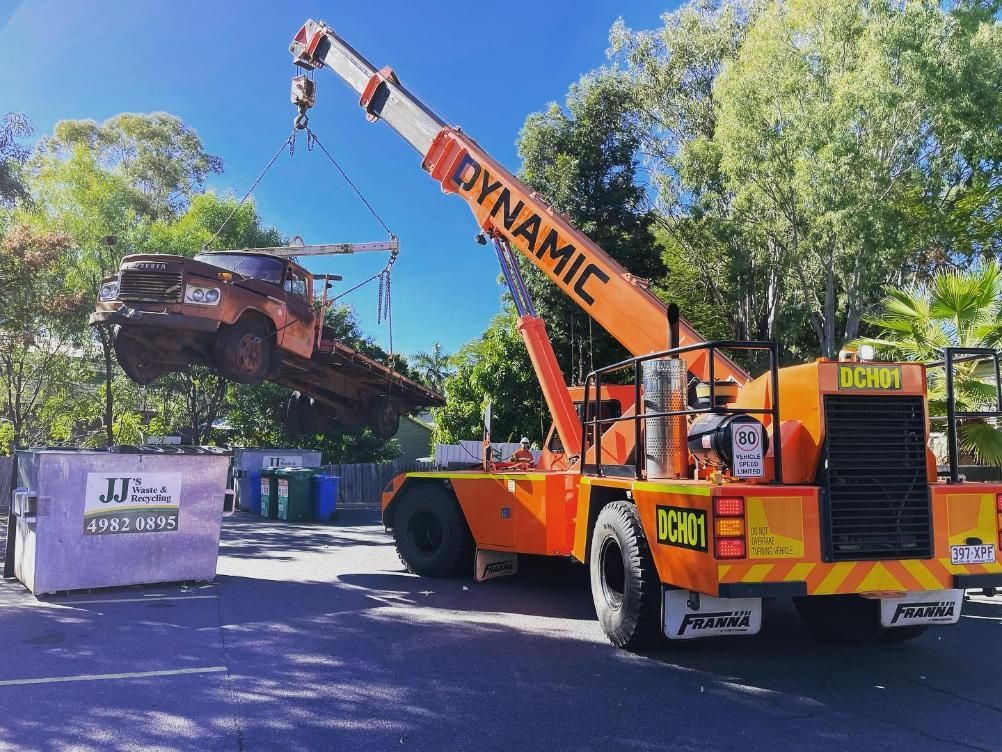 An Orange Dynamic Crane Is Lifting A Truck — Dynamic Crane Hire In Capella, QLD