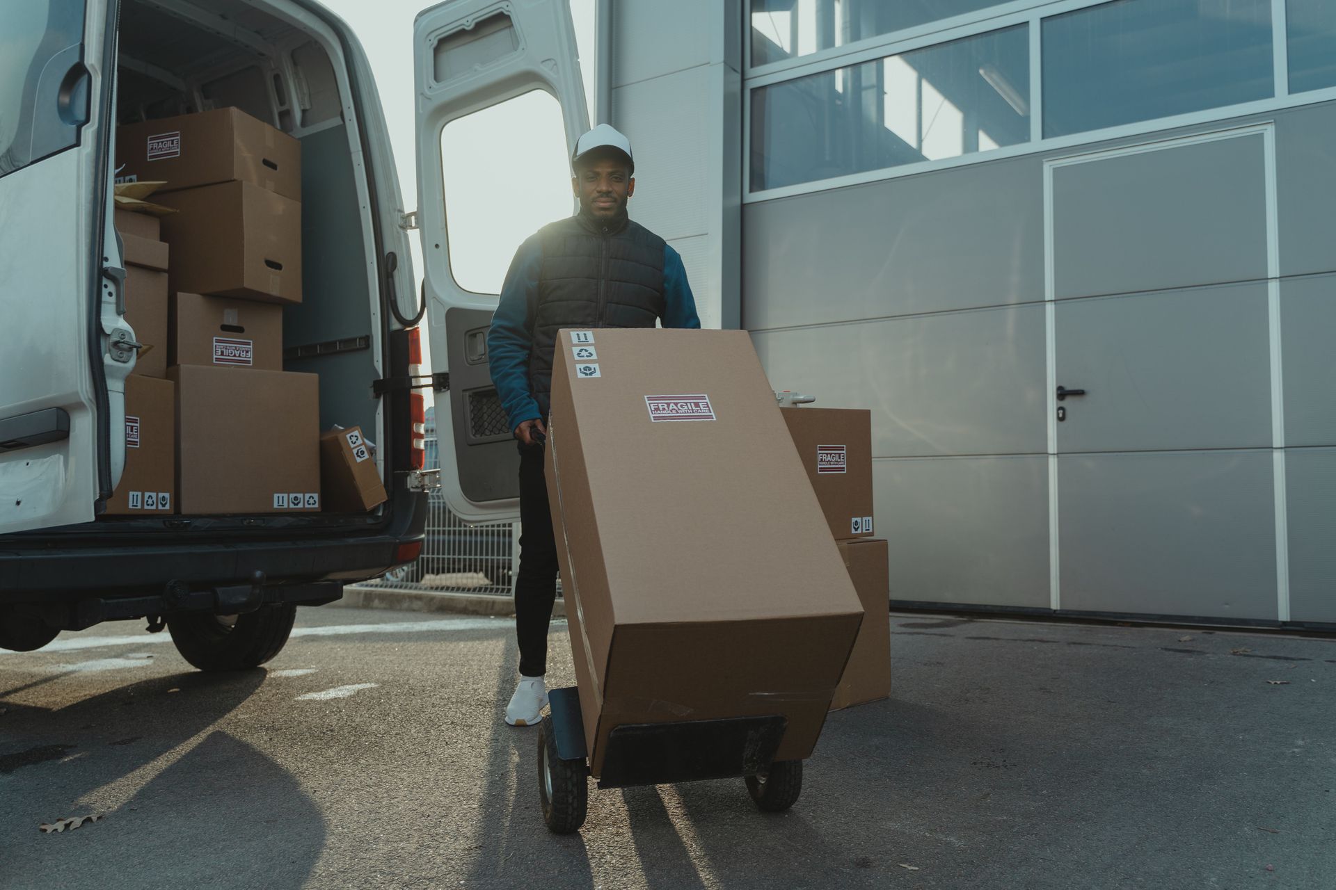 Worker unloading cardboard boxes from a delivery van outside a warehouse