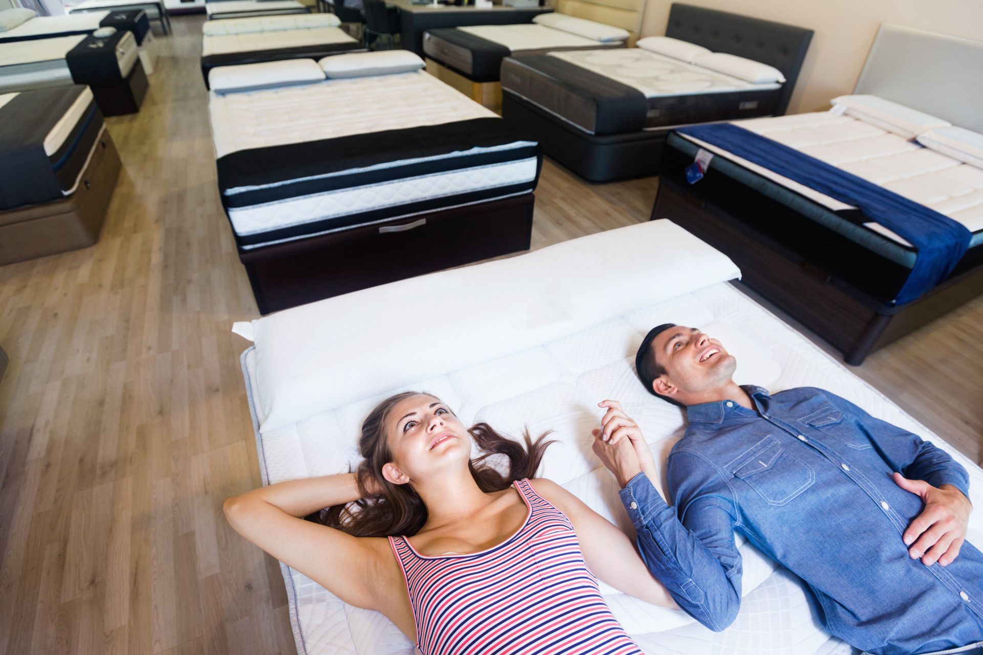 Two people lying on the floor in a mattress showroom, looking up at the ceiling. Two people lying on the floor in a mattress showroom, looking up at the ceiling.