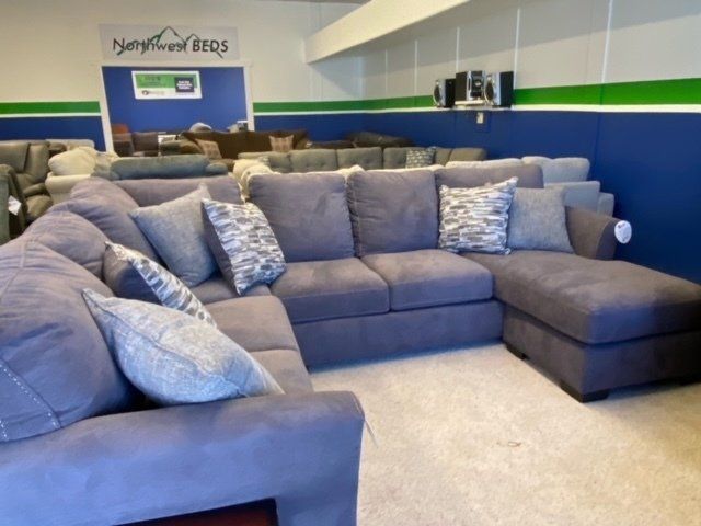 A large, gray sectional sofa with accent pillows displayed in a furniture store showroom.