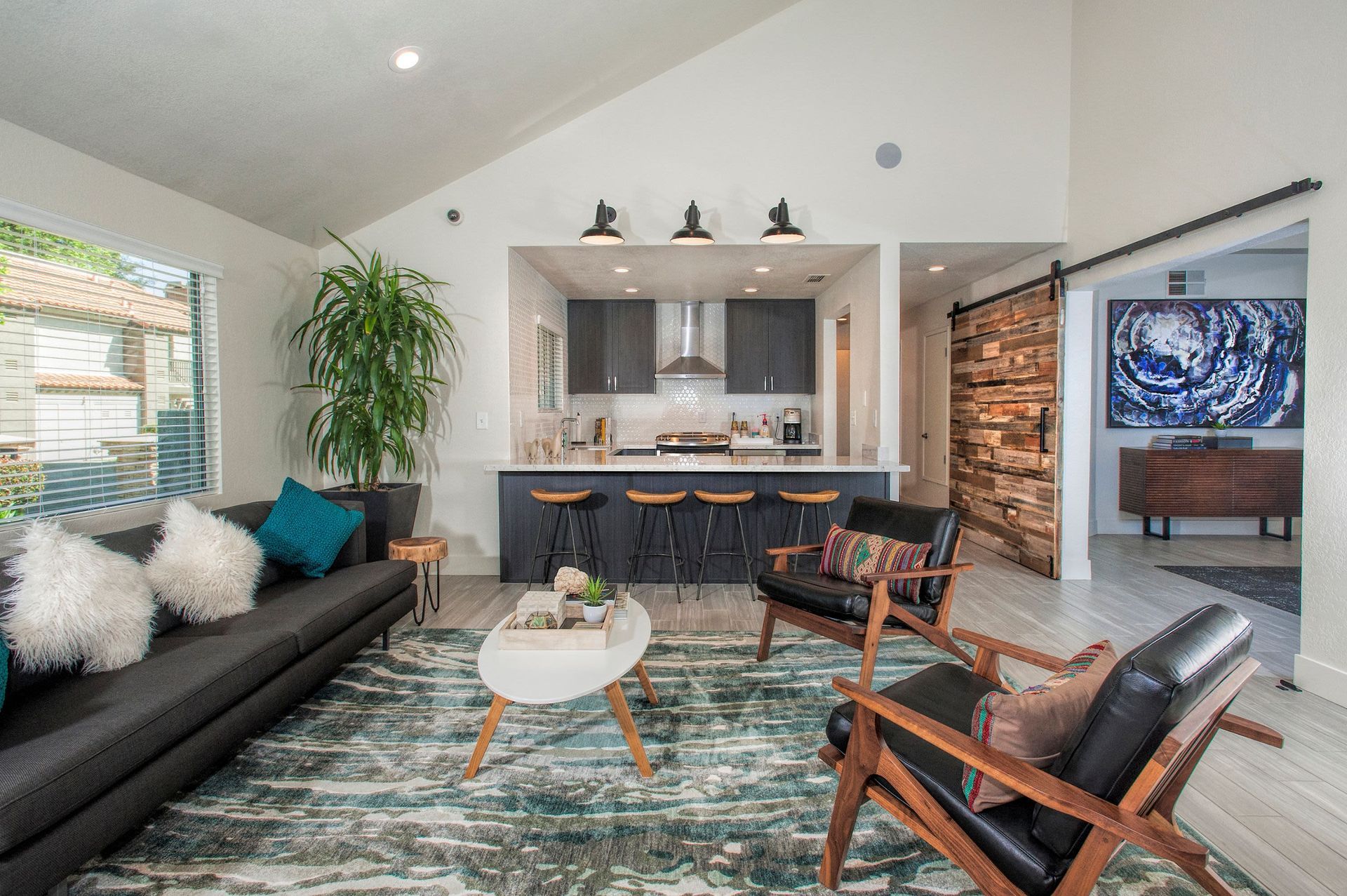 Open-concept living area with a kitchen island, bar stools, and modern furnishings at Shore Park at Riverlake.