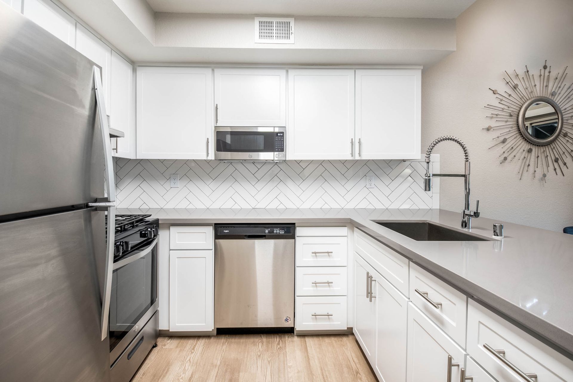White modern kitchen with stainless steel appliances and a large sink at Shore Park at Riverlake.