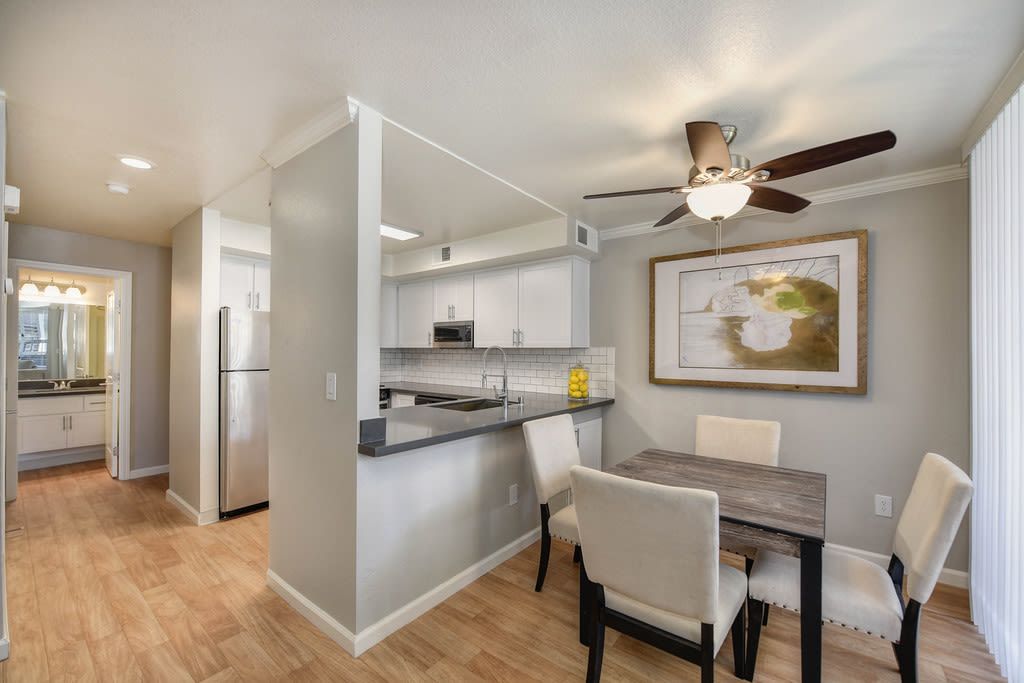 Open-concept kitchen and dining area with white cabinets, stainless fridge, and a dark island at Shore Park at Riverlake.
